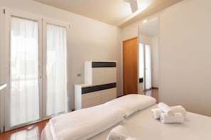 Ein Schlafzimmer mit einem Bett, einer Kommode, einem Spiegel und einer Schiebetür.