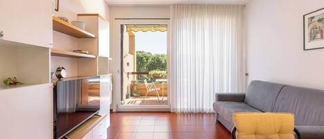 Uma sala de estar moderna com sofá, TV e varanda com vista.