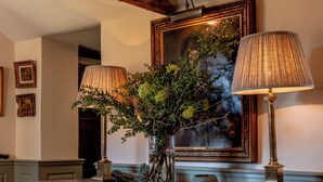 Un bureau en bois, deux lampes, un vase avec des plantes et un tableau encadré accroché au mur.