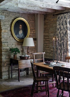 A rustic dining room with a stone wall, a wooden table, and chairs.