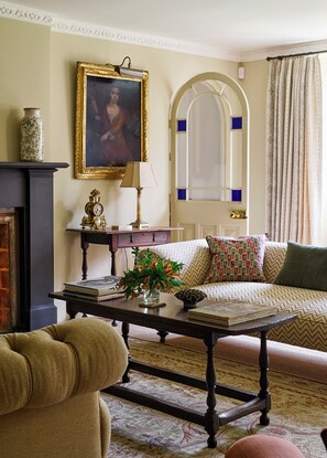 A living room with a sofa, a table with a vase of flowers, a clock, and a framed painting.