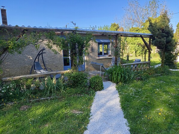 A rustic house with a gravel path leading to a patio area with outdoor seating.