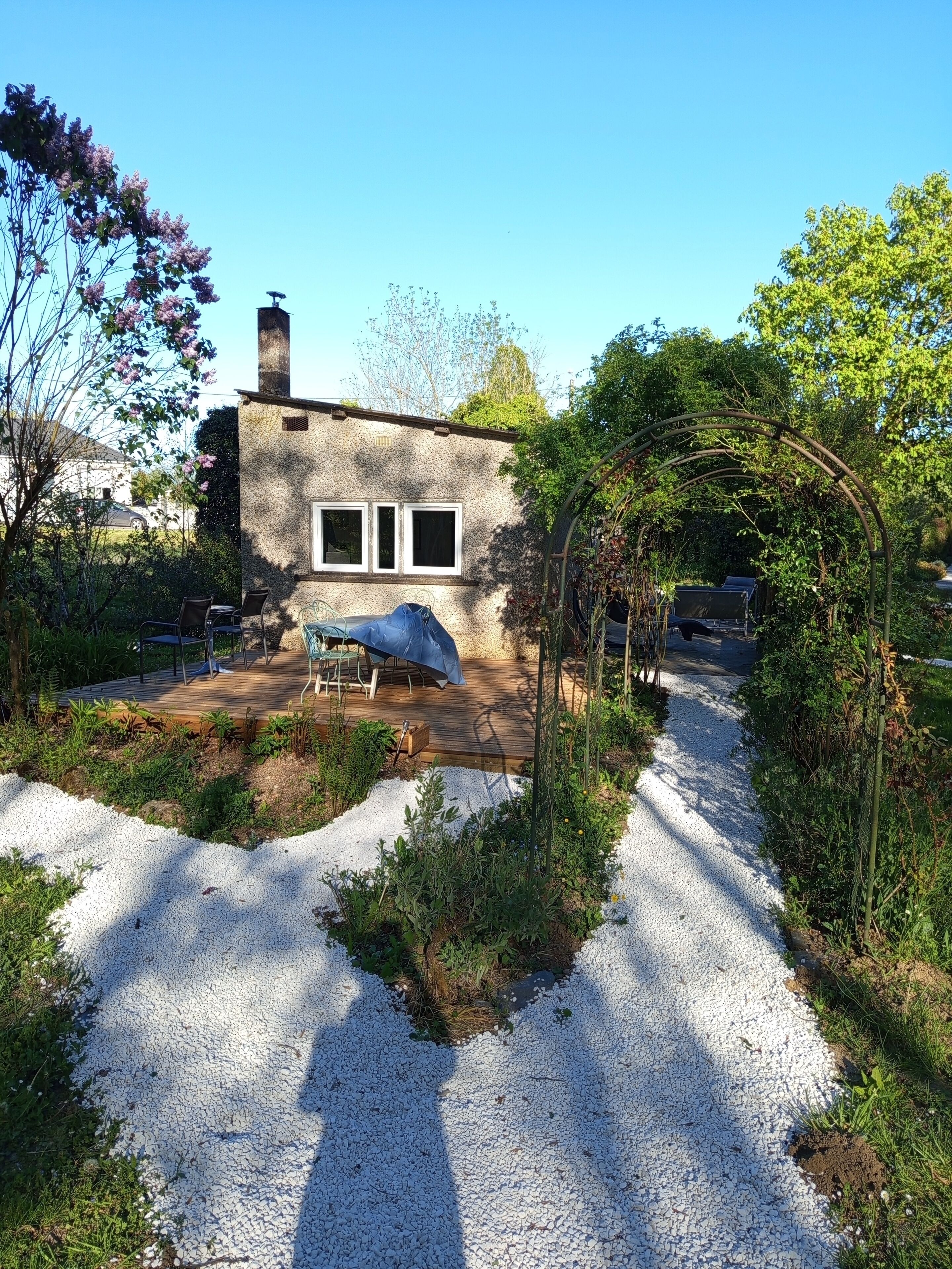 Ein Haus mit einem Schotterweg, einer Holzterrasse und einer überdachten Veranda.