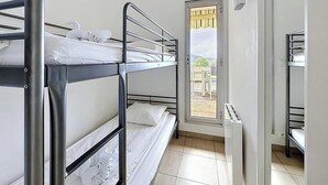 Ein Schlafzimmer mit Etagenbetten, einem Fenster, einer Tür und Blick ins Freie.