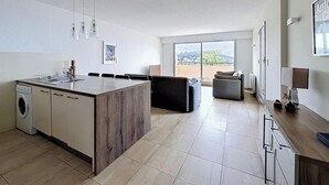 Eine moderne Küche mit Kochinsel, Essbereich mit Stühlen, Sofa und großem Fenster mit Aussicht.