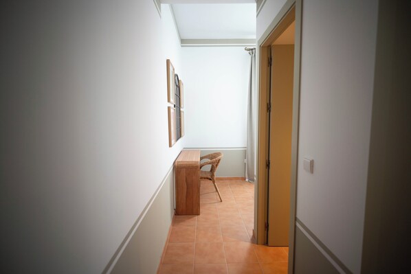 A narrow hallway with a wooden bench, a door, and a wall-mounted picture frame.