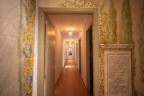 Un pasillo con una lámpara en forma de estrella, una puerta a la izquierda y un panel decorativo en la pared derecha.