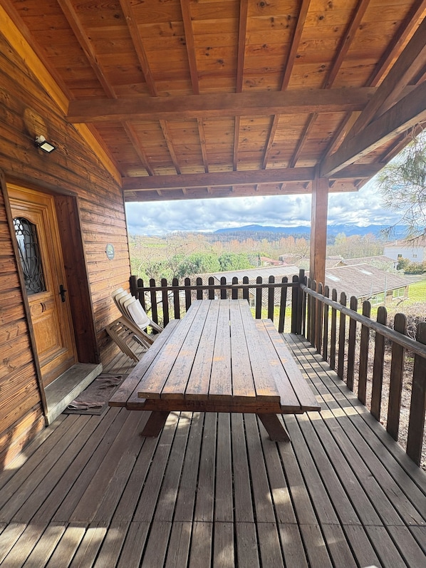 A wooden deck with a picnic table, a wooden door, and a view of mountains.