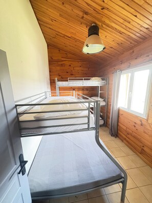 Une chambre avec un lit superposĂ©, un plafond en bois et une fenĂȘtre.
