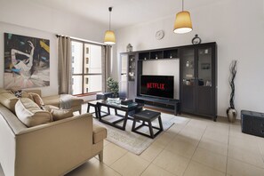 A living room with a sofa, coffee table, TV, and decorative items. - Spacious 2 Bedroom Apt in Sadaf JBR  (Dubai)