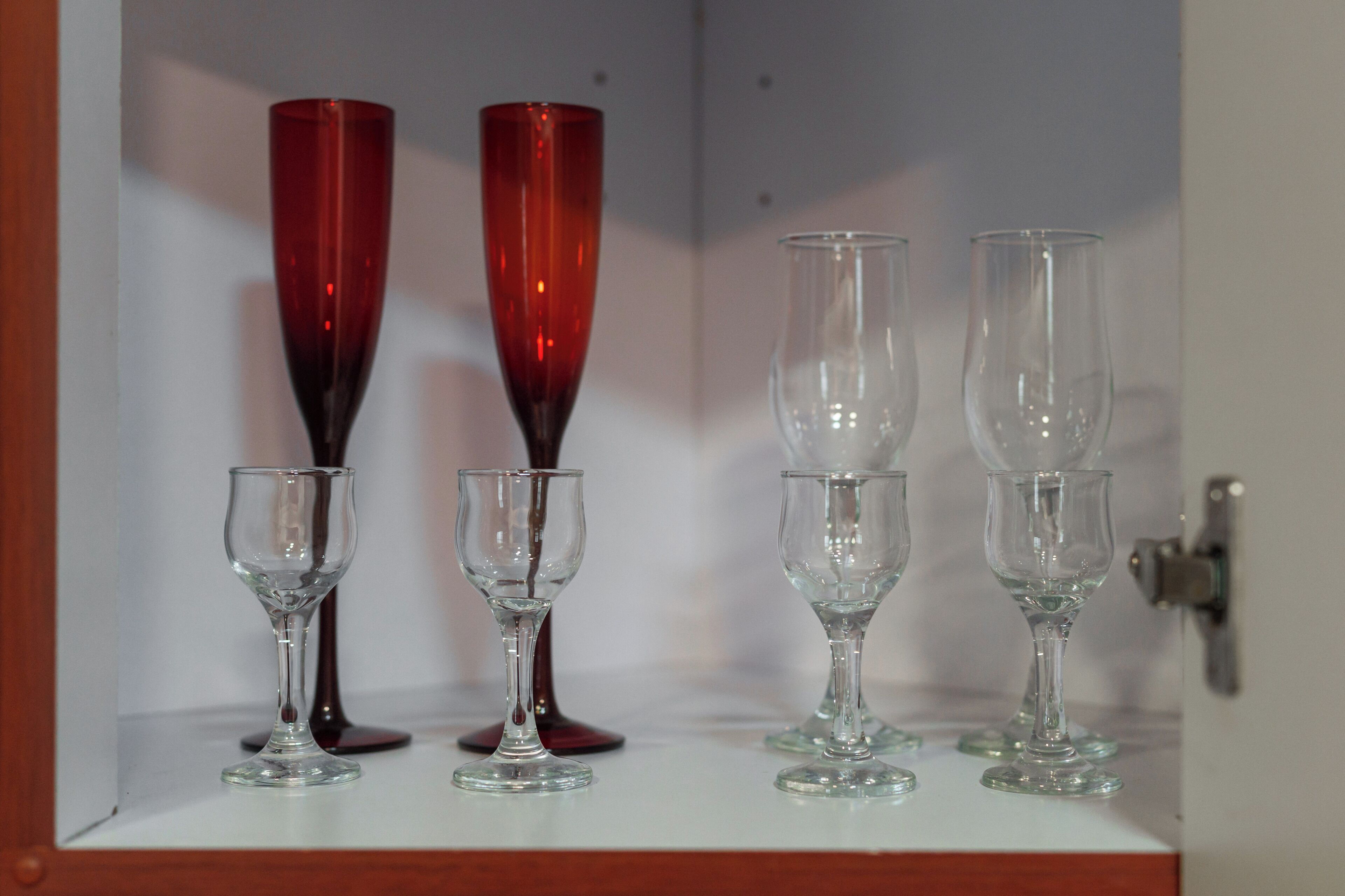 A set of four wine glasses on a shelf.