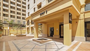 A hotel entrance with a sign reading 'SADAF 2', a covered outdoor area, and a water feature. - Spacious 2 Bedroom Apt in Sadaf JBR  (Dubai)
