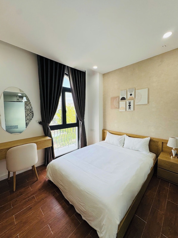A hotel room with a large bed, a desk, a chair, a nightstand, and a window with curtains. - Stayla Homestay Grand World Phu Quoc (Phu Quoc)