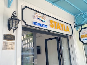 A Stayla Homestay sign with a traditional lantern and a street sign.