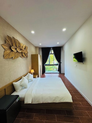 A hotel room with a bed, a TV mounted on the wall, a decorative wall piece, and a view through the window. - Stayla Homestay Grand World Phu Quoc (Phu Quoc)