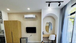 Un soggiorno moderno con un divano, due poltrone, una TV, un tavolino e uno specchio.