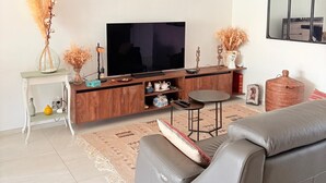 Ett modernt vardagsrum med en platt-TV, en soffa, ett soffbord och dekorativa föremål.