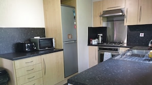 A kitchen with a microwave, toaster, refrigerator, stove, sink, and wooden cabinets. - Wooden 3-bed Lodge, Sleeps 9/10 With Front Decking (Fleetwood)