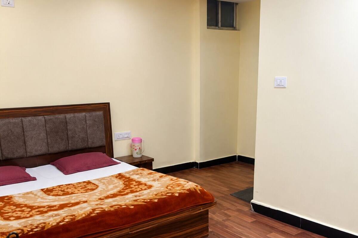 Un dormitorio con una cama de madera, una mesita de noche y una pequeña mesa con un recipiente rosa.