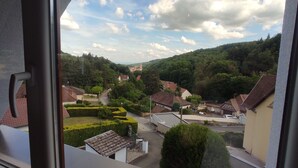 A residential area with houses, a church, and a hill with trees. - The edge of the vineyard - the balcony (Andlau)