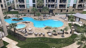 A pool area with lounge chairs and a small pool, surrounded by a fence and greenery. - Dog-friendly & spacious condo with lake views, large balcony, & Pool (Horseshoe Bay)
