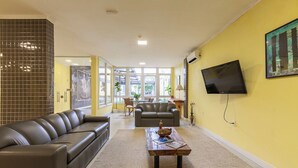 A living room with a sofa, a coffee table, and a TV mounted on the wall. - TRI HOTEL SMART SANTA MARIA (Santa Maria)