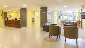 A hotel lobby with a reception desk, seating area, and large windows. - TRI HOTEL SMART SANTA MARIA (Santa Maria)