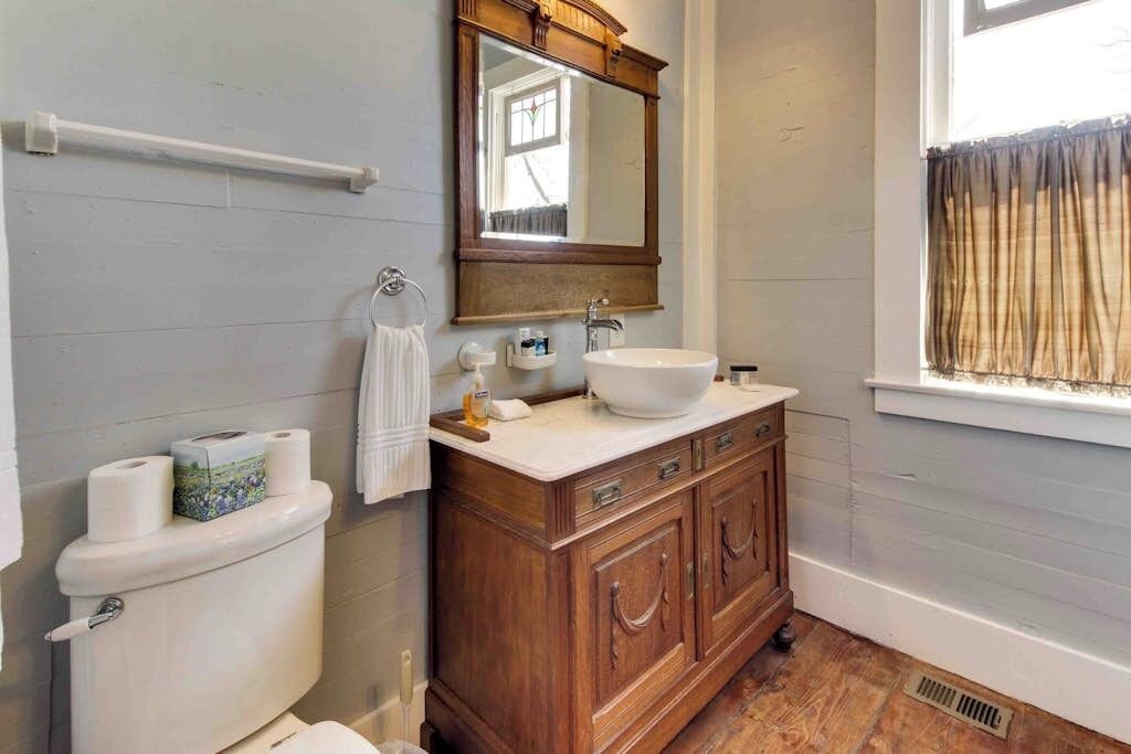 Un bagno con il water, un mobile bagno in legno, un lavandino bianco e uno specchio sopra il mobile.