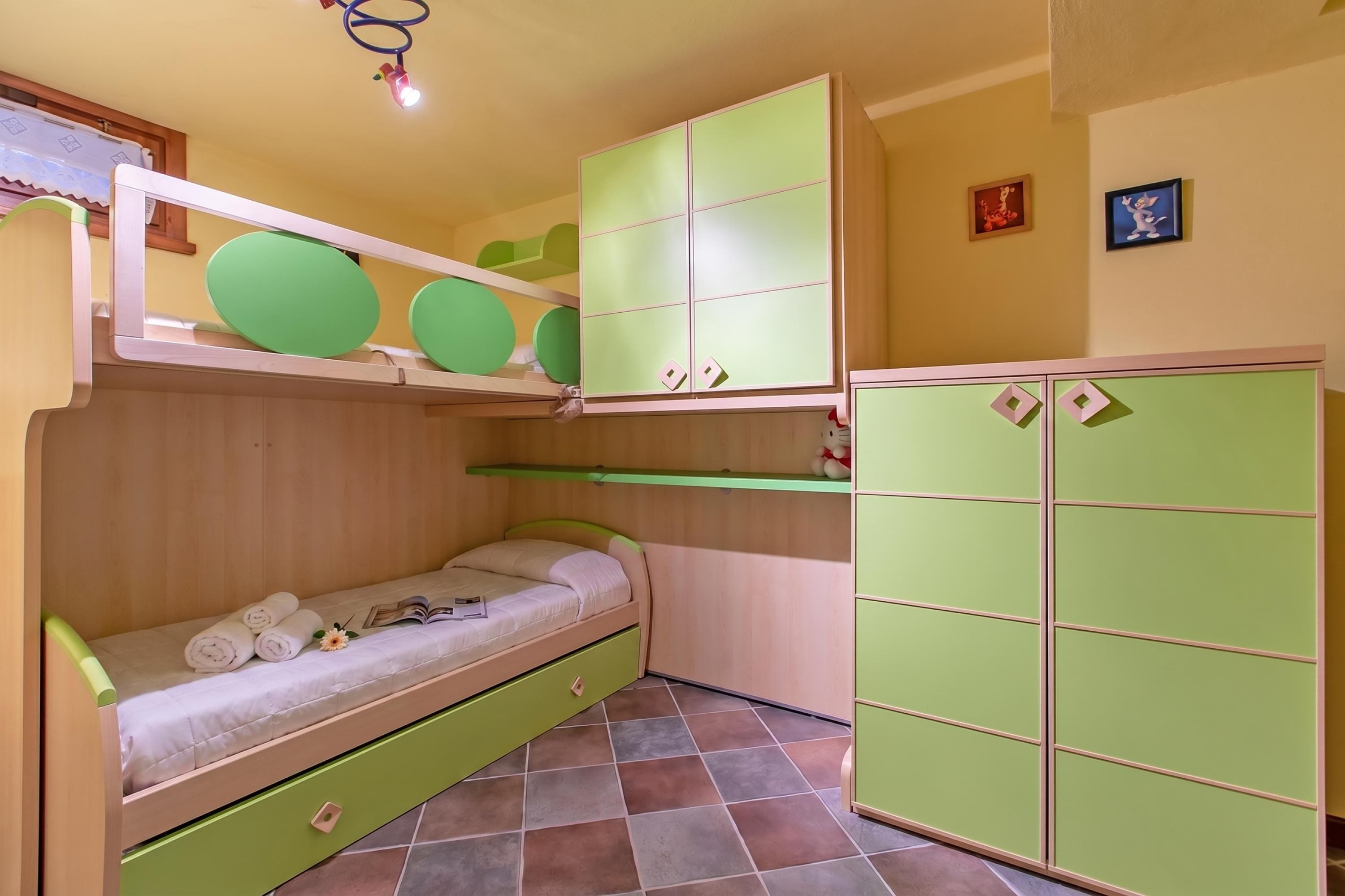 Quarto com beliche, guarda-roupa verde e prateleira com objetos verdes.