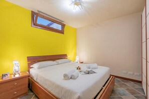 A bedroom with a bed, bedside tables, a nightstand, a window, and a ceiling light fixture. - La Casa Di Olaf (Bardonecchia)