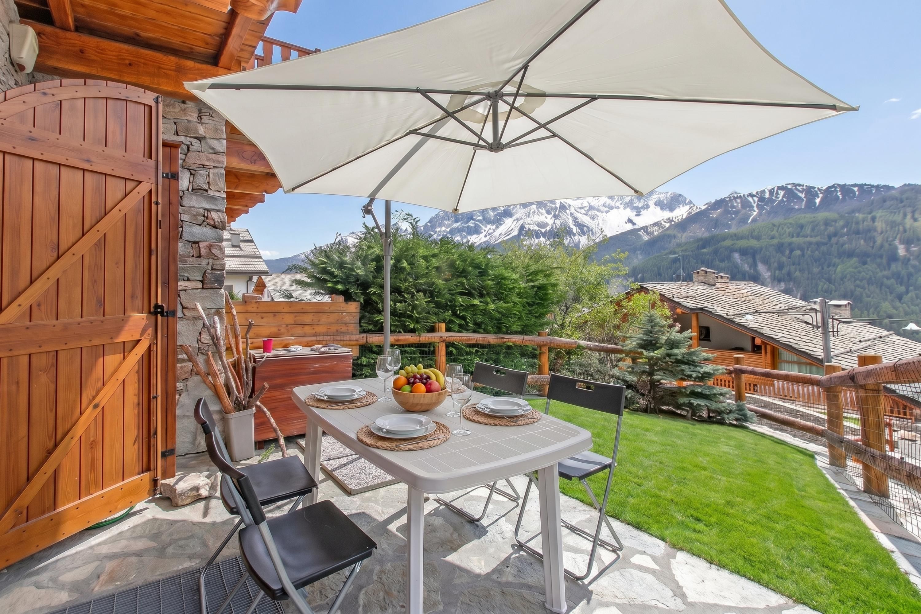 A patio with a table set for dining, a wooden gate, and a mountain view.