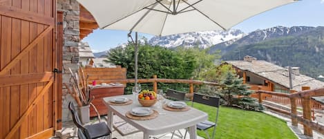 A patio with a table set for dining, a wooden gate, and a mountain view.