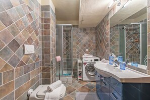 Ein Badezimmer mit Dusche, Waschmaschine, Toilette und Waschbecken.