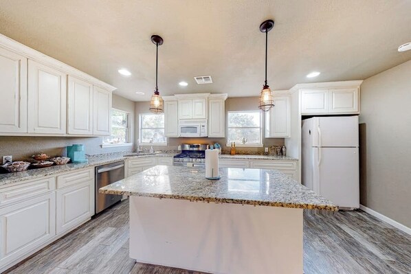 A kitchen with white cabinets, granite countertops, a central island, stainless steel appliances, and pendant lighting. - Secluded, Dog-Friendly Getaway w/ Beautiful Views, a Large Yard, & Free WiFi (Fredericksburg)