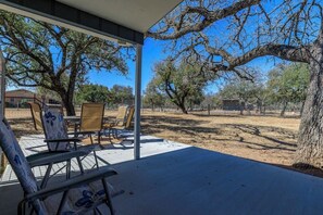An outdoor patio with chairs and a table, surrounded by trees and a fenced area. - Secluded, Dog-Friendly Getaway w/ Beautiful Views, a Large Yard, & Free WiFi (Fredericksburg)