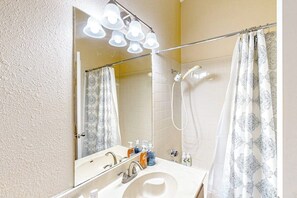 A bathroom with a sink, mirror, shower, and patterned shower curtain. - Golf course-view home with yard, grill, AC, & W/D - dog-friendly (Lago Vista)