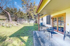 Un patio couvert avec une table et des chaises, une cour clôturée et un bâtiment comprenant un garage.