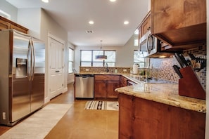 A modern kitchen with stainless steel appliances, wooden cabinets, and a granite countertop.