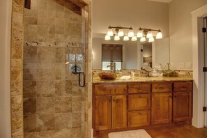 A bathroom with a shower, a vanity with a large mirror, and a wooden cabinet.