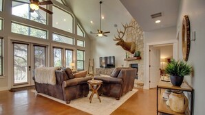 A spacious living room with a large window, a fireplace, and a mounted deer head.