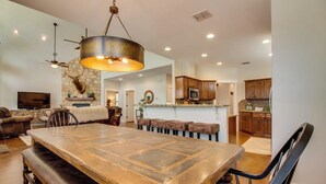 A spacious dining area with a large wooden table and benches, a hanging light fixture, and a stone accent wall.