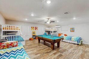 Une pièce avec une table de billard, des lits superposés et un ventilateur de plafond.