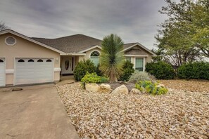 Ein Wohnhaus mit Garage, ein gepflegter Garten mit Steinen und Pflanzen sowie eine Palme.