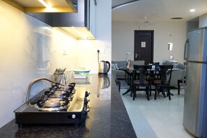 Une cuisine moderne équipée d’une cuisinière à gaz, d’un coin repas avec une table et des chaises, et d’un réfrigérateur.