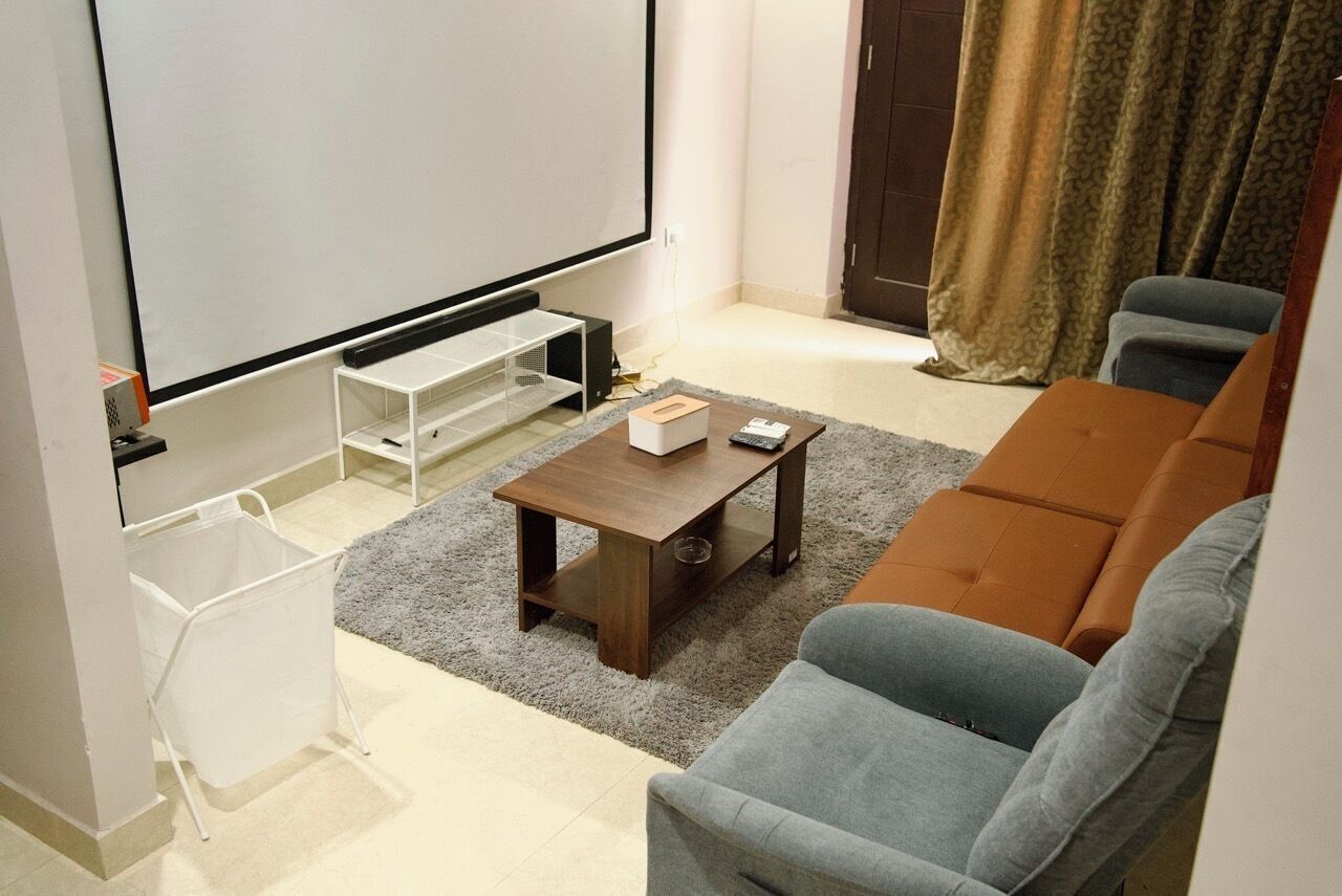 Een woonkamer met een bank, een salontafel, een televisie en een witte wasmand.