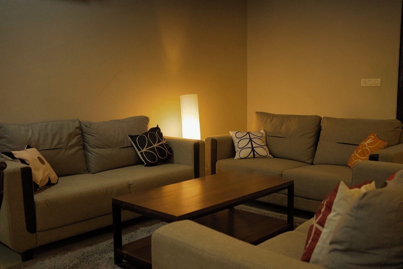 Uma sala de estar com dois sofás, uma mesa de centro e uma luminária.