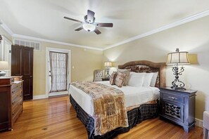 A bedroom with a bed, a ceiling fan, a nightstand, a dresser, and a door. - Peaceful home right near downtown - walk everywhere, 2 dogs welcome (Fredericksburg)