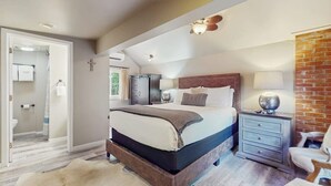 Ein Schlafzimmer mit einem Bett, Nachttischen, einer Kommode und einer Backsteinwand.