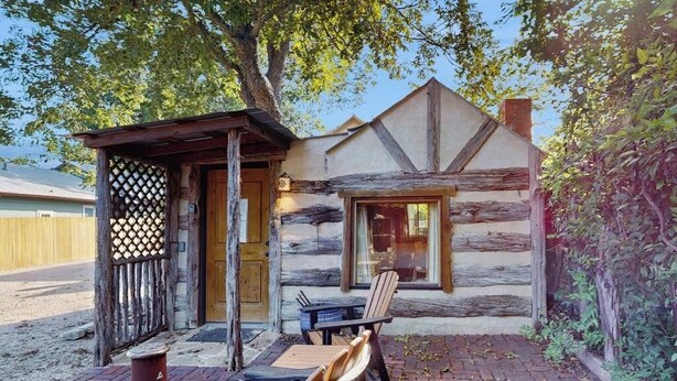 Eine rustikale Holzhütte mit einer Holzterrasse, einem überdachten Sitzbereich und einem Fenster.