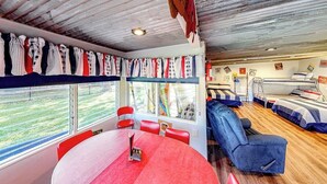 Ein Zimmer mit Etagenbetten, einem Esstisch und einem Fenster mit Blick ins Freie.